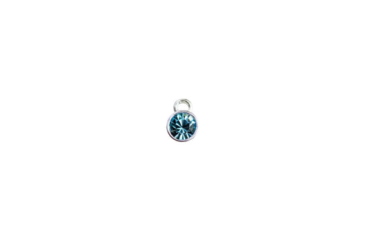 silver charm with blue crystal on a white surface