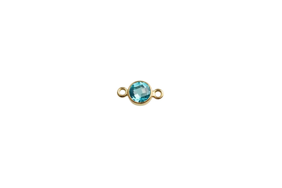 Gold charm with a blue gemstone on a white background