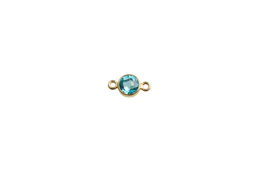 Gold charm with a blue gemstone on a white background