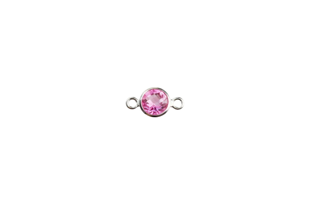 Silver charm with a pink gemstone on a white background