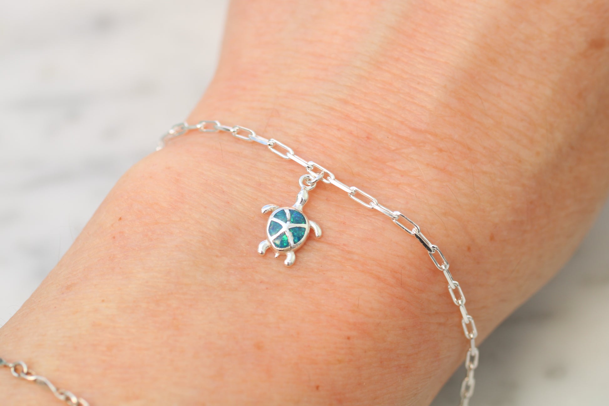 Silver turtle bracelet on a wrist with a blurred background