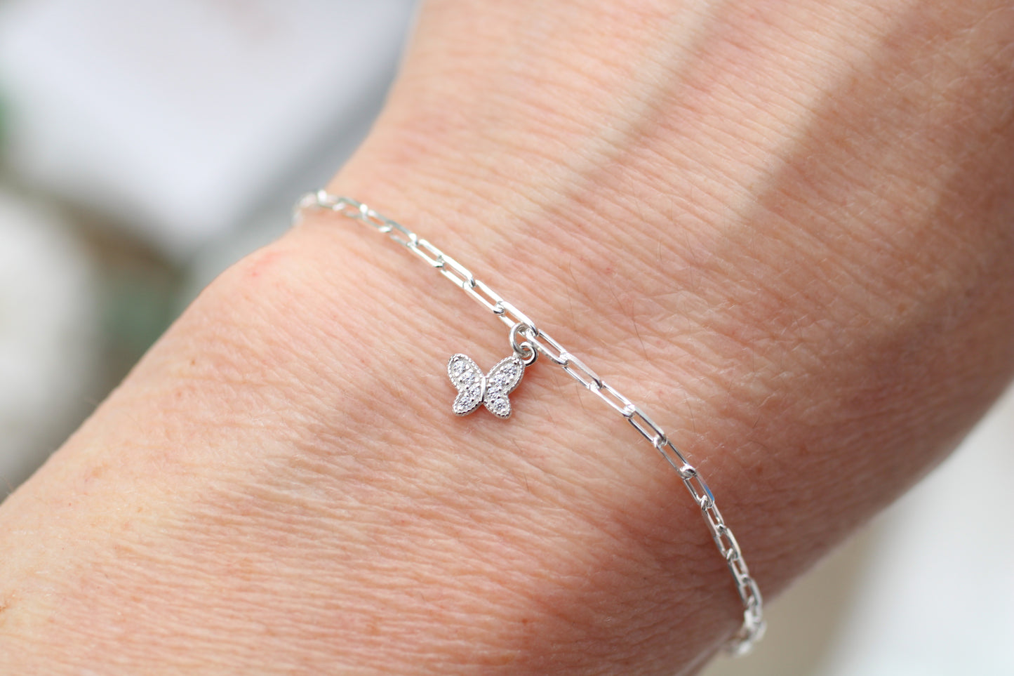 Silver butterfly bracelet on a person's ankle with a blurred background