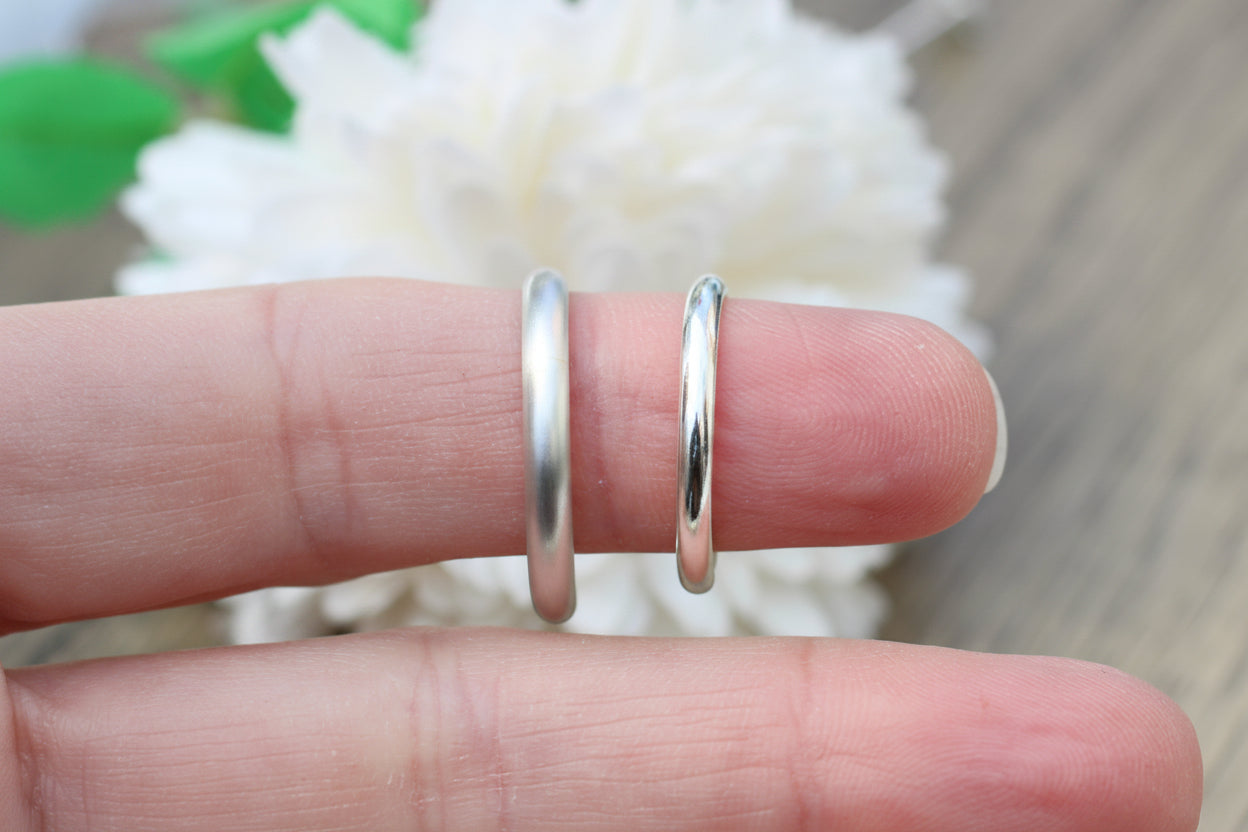 Two silver rings on a finger with a blurred floral background