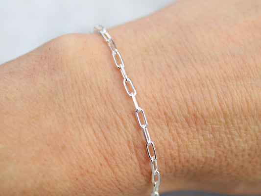 Silver chain bracelet on a wrist against a neutral background