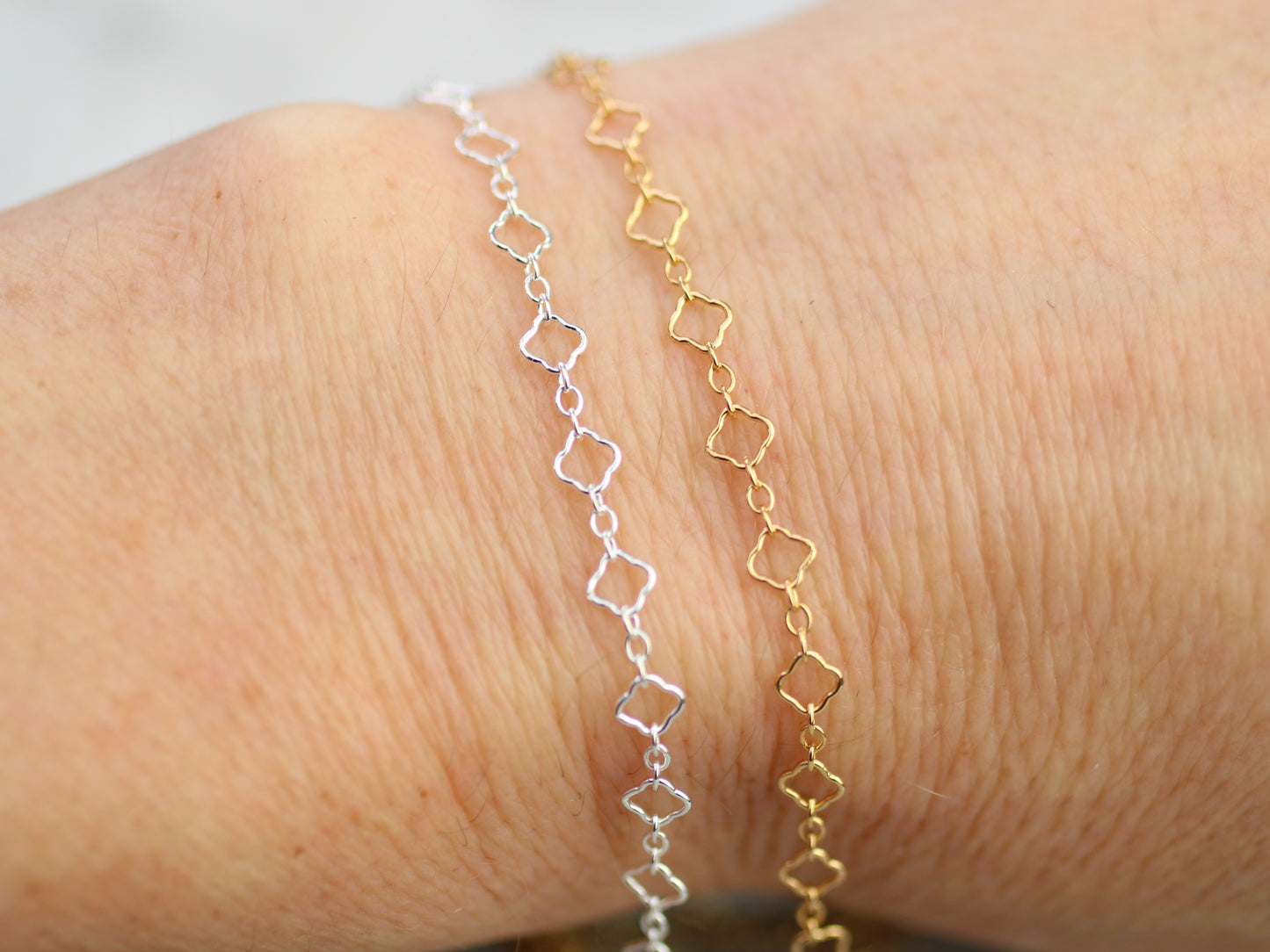 Two gold and silver bracelets on a wrist against a neutral background