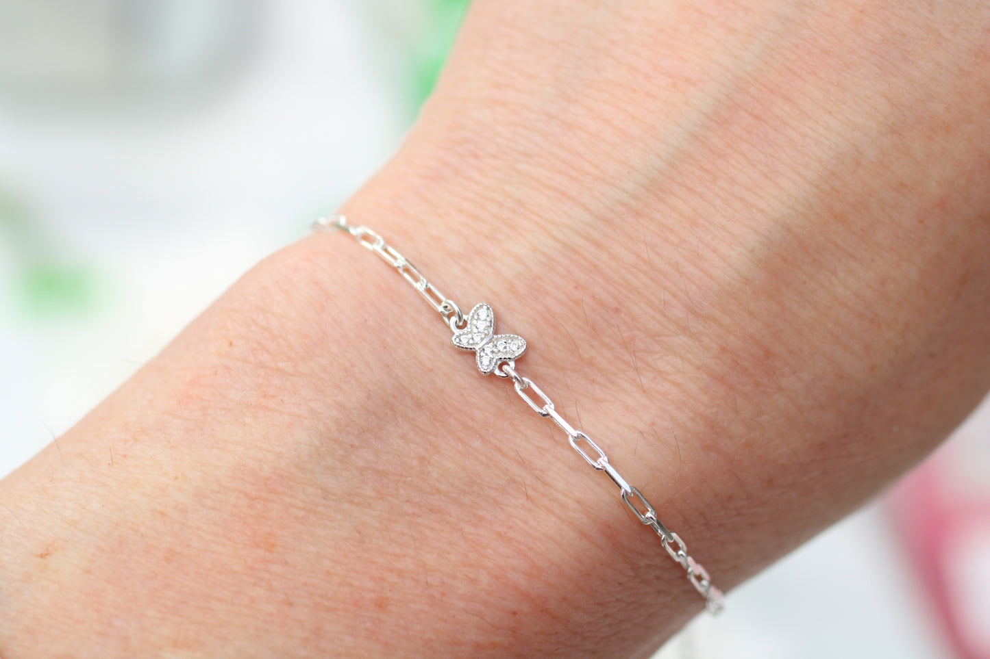 Silver butterfly bracelet on a wrist with a blurred background