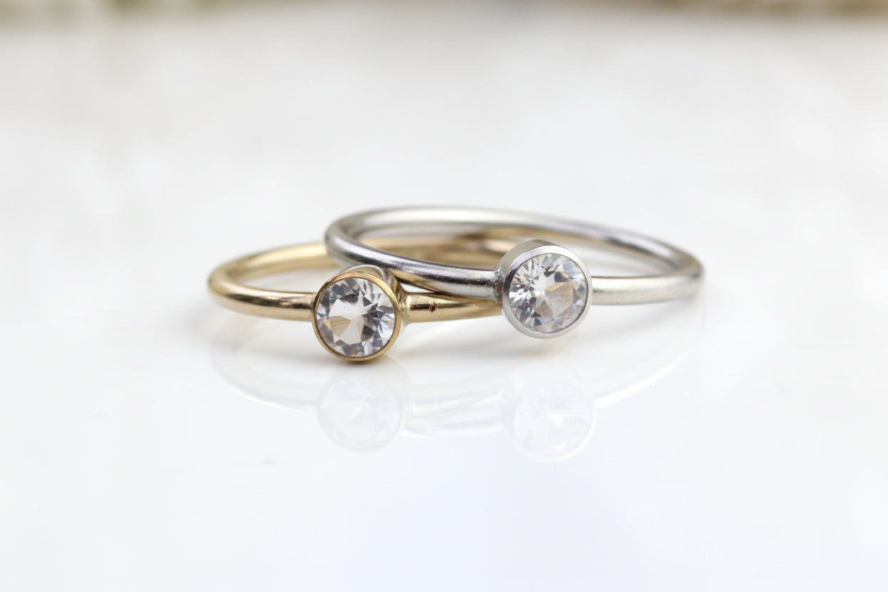 Two gold rings with embedded crystals on a light background