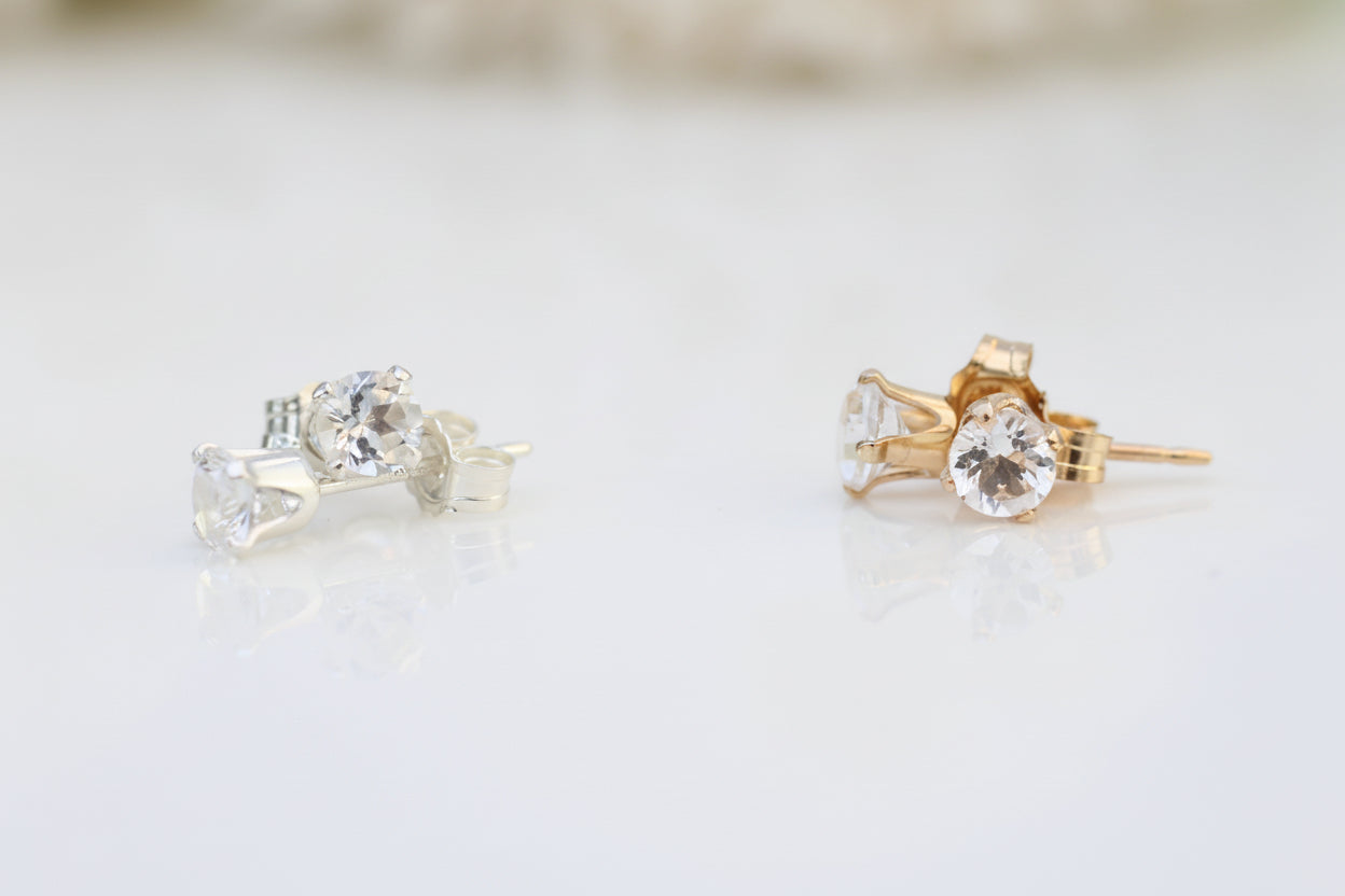 Pair of gold and silver stud earrings on a light background