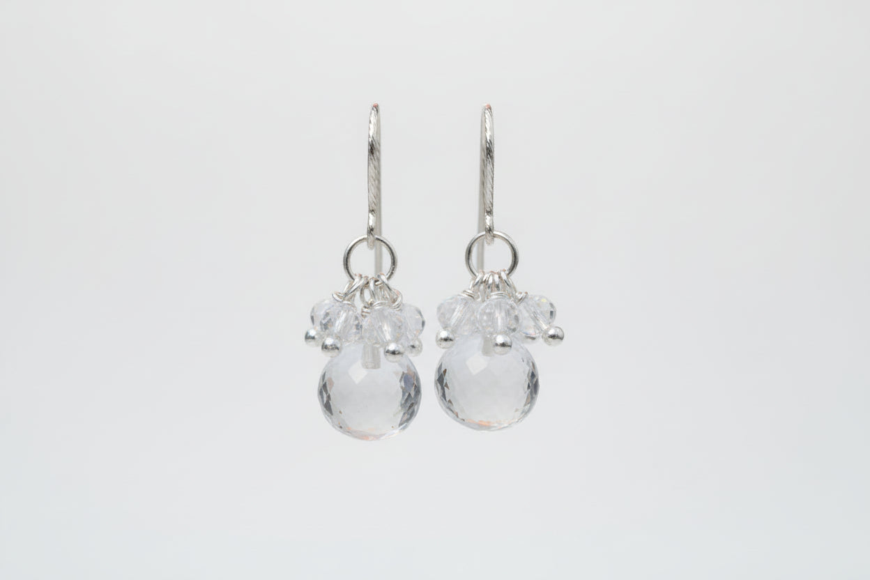 Silver earrings with clear beads on a white textured surface