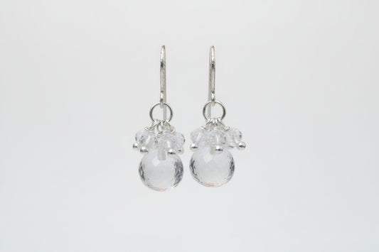 Silver earrings with clear beads on a white textured surface