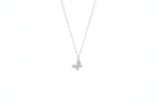 Silver butterfly necklace on a marble surface with white flowers in the background