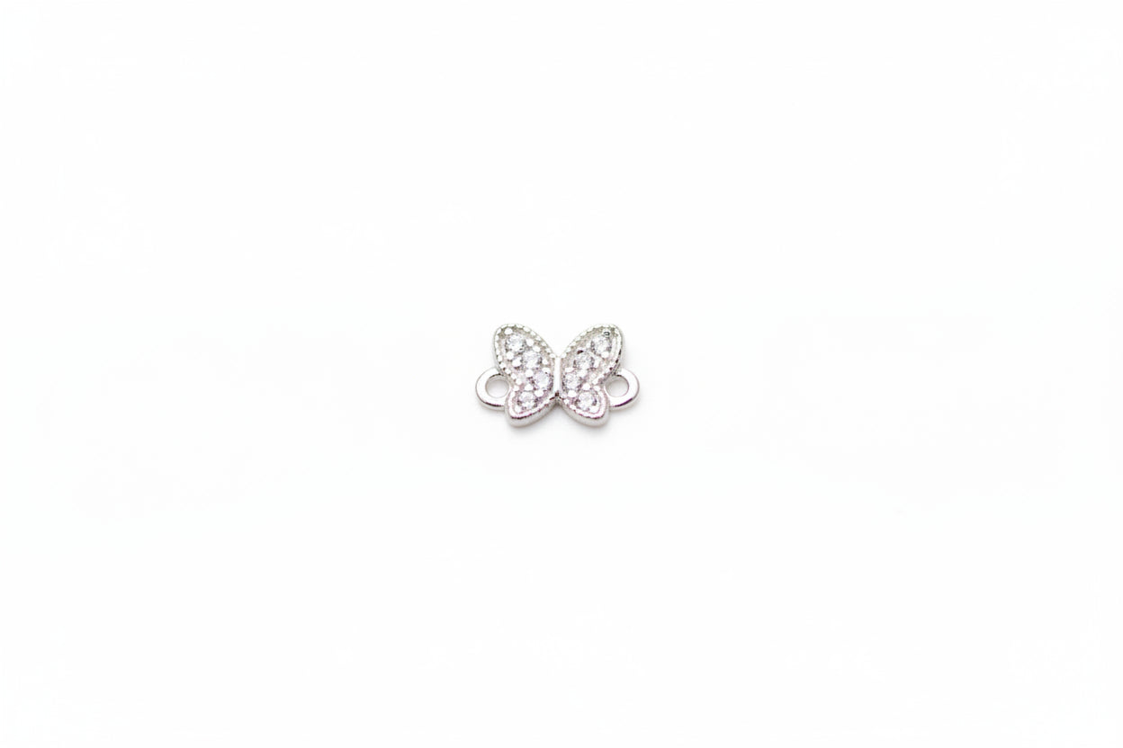 Butterfly-shaped jewelry charm on a light marble background
