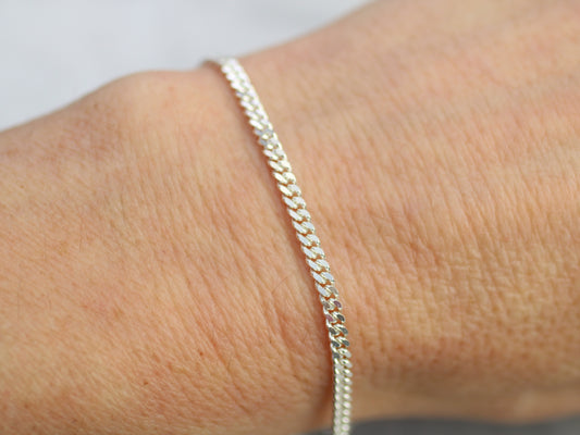 Silver bracelet on a wrist with a plain background