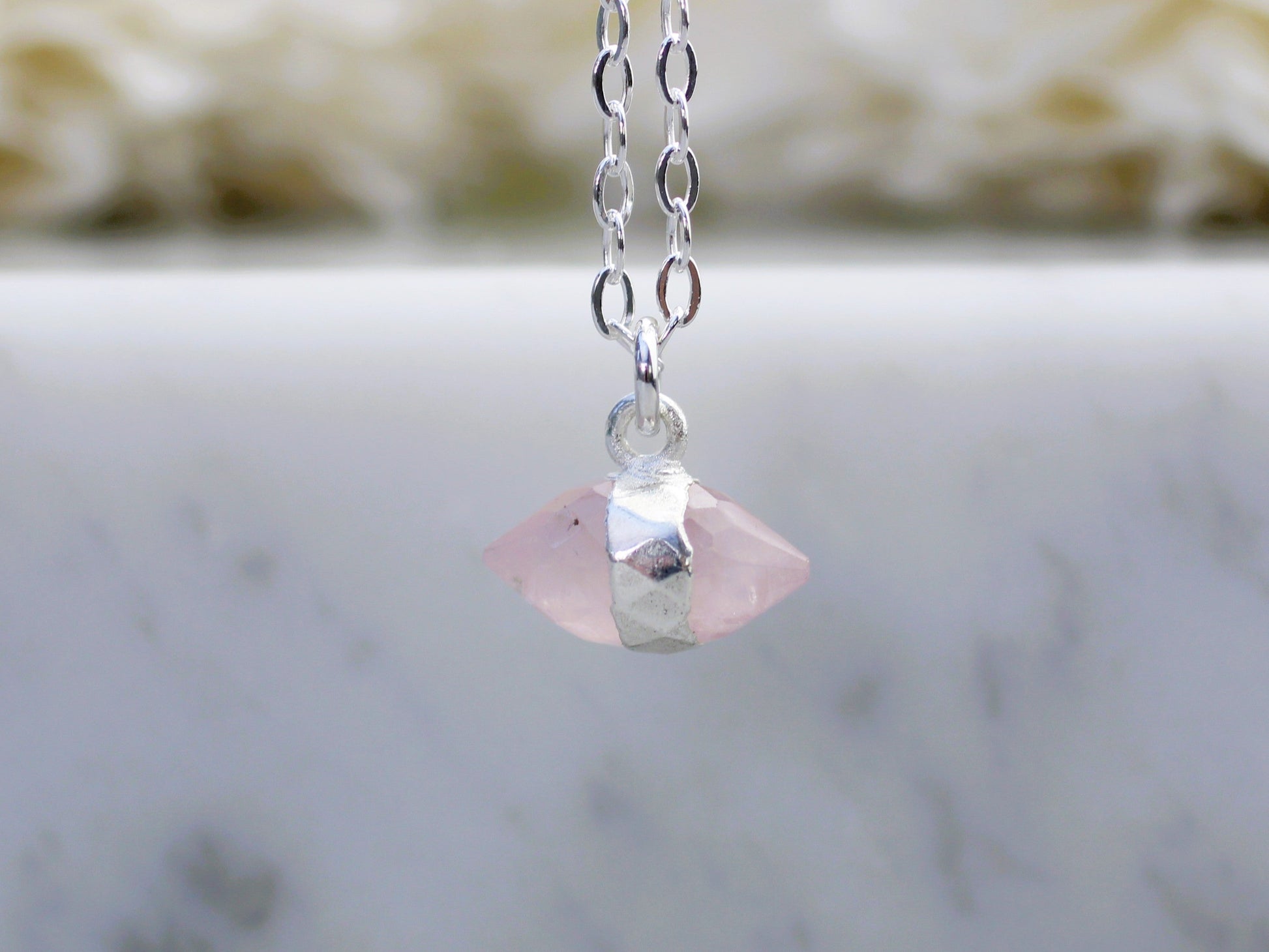 Necklace with a pink crystal pendant on a marble surface