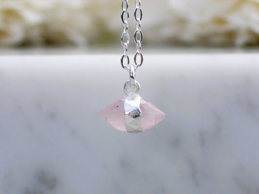 Necklace with a pink crystal pendant on a marble surface