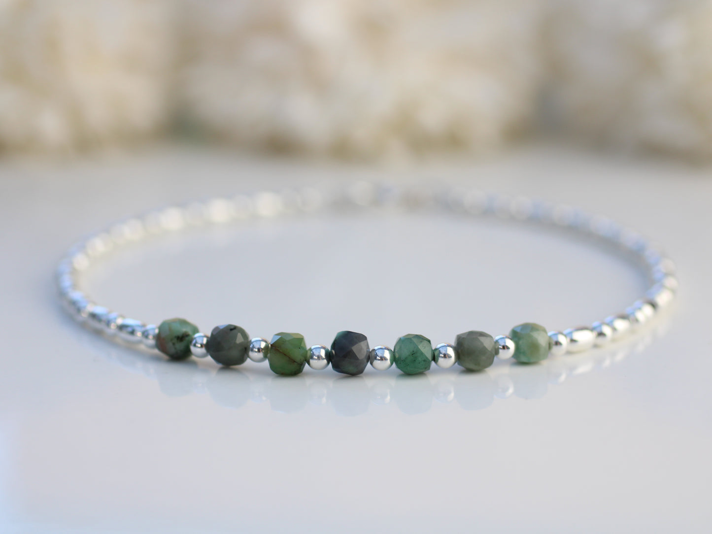 Bracelet with green beads and silver accents on a light background