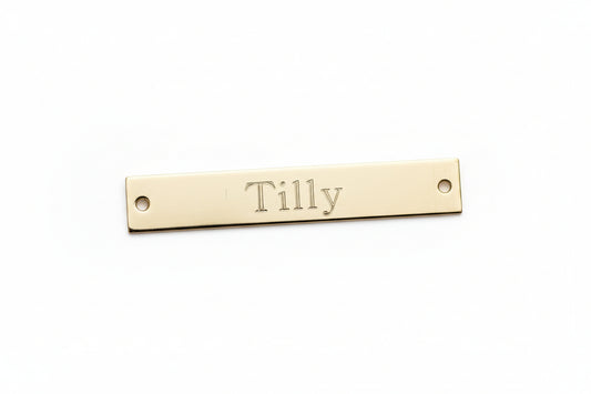Gold nameplate with 'Tilly' engraved on a marble background
