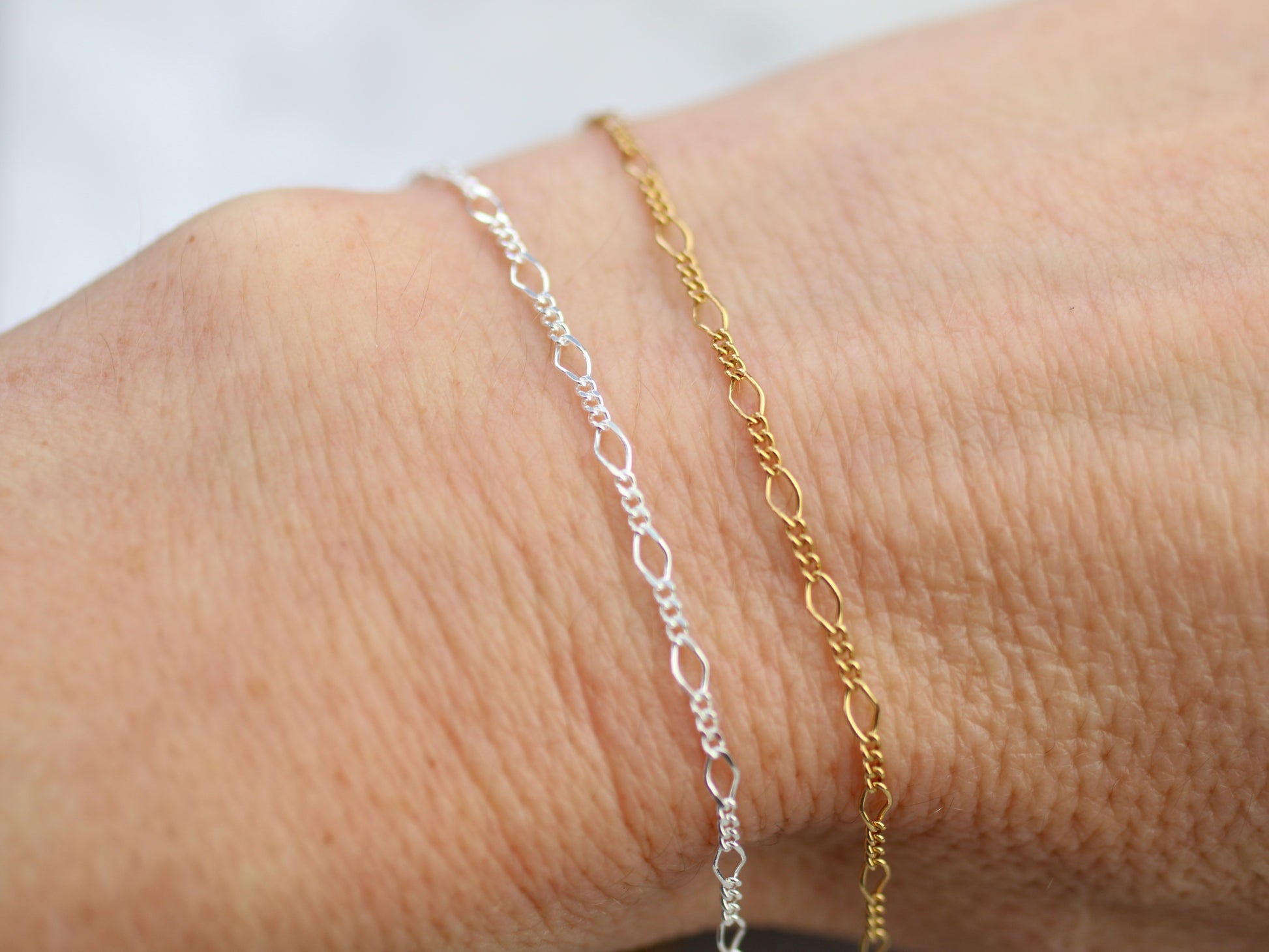 Two gold and silver bracelets on a wrist against a white background