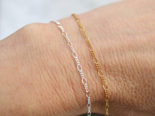Two gold and silver bracelets on a wrist against a white background