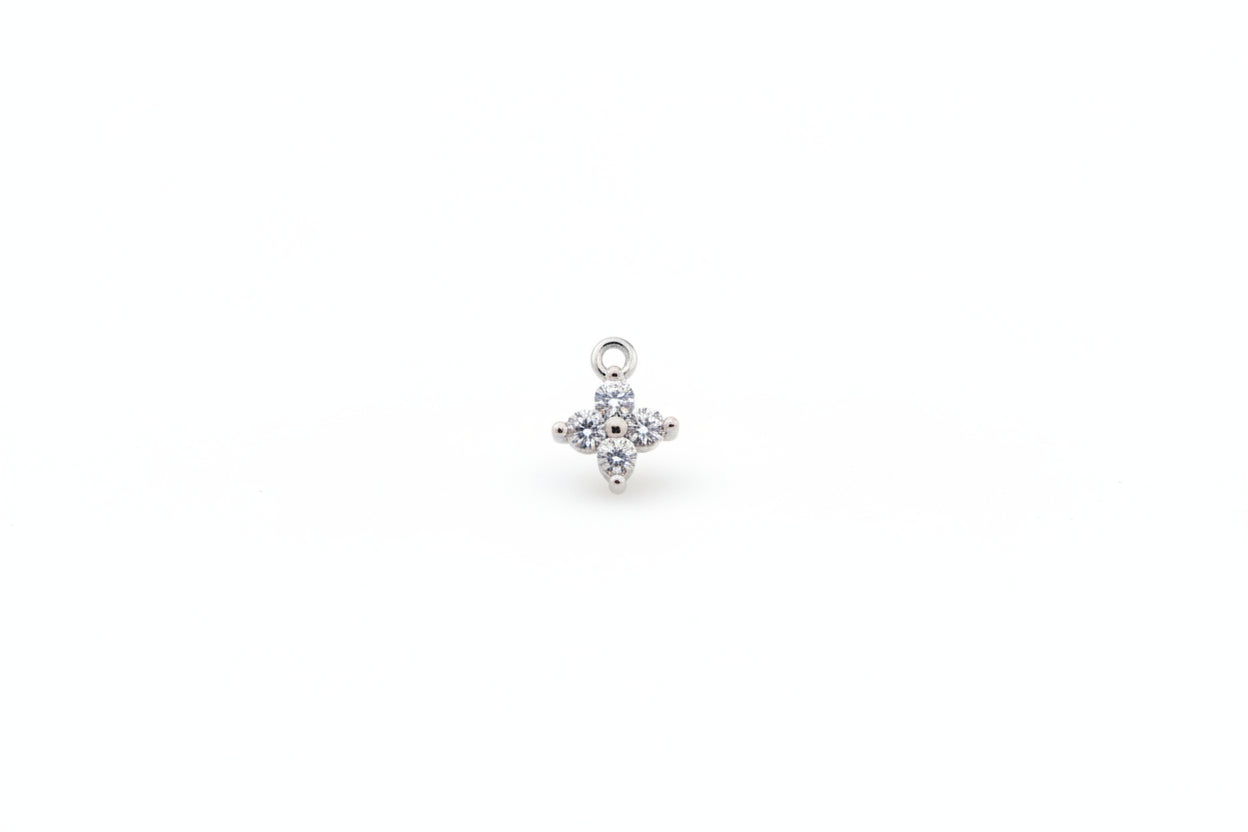 Silver flower-shaped pendant with clear stones on a marble background