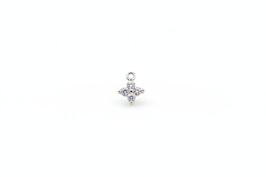 Silver flower-shaped pendant with clear stones on a marble background