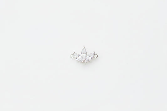 A small silver crown charm with clear rhinestones, displayed on a white marble surface.