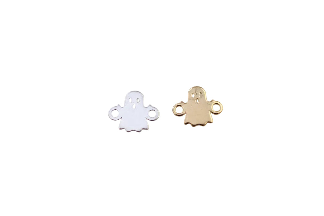 Two ghost-shaped charms, one white and one gold, on a light gray background.
