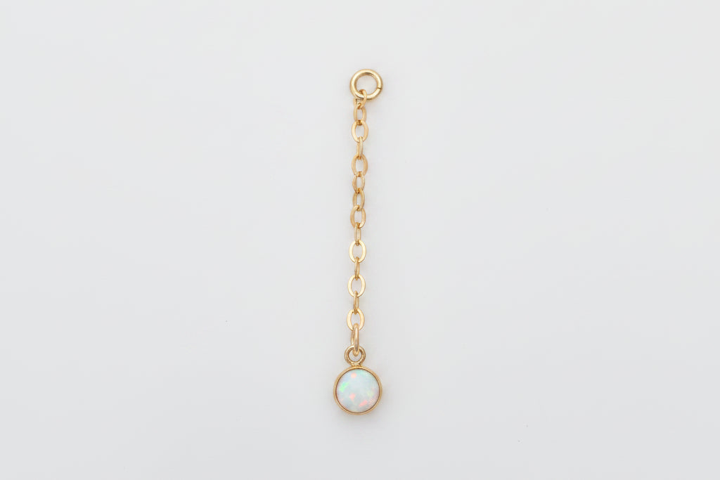Gold chain with a small round pendant on a marble background