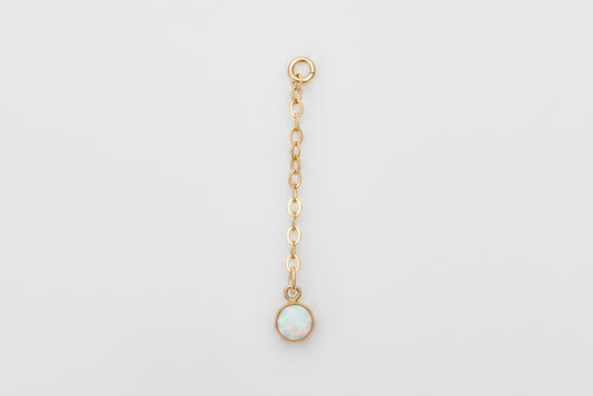 Gold chain with a small round pendant on a marble background