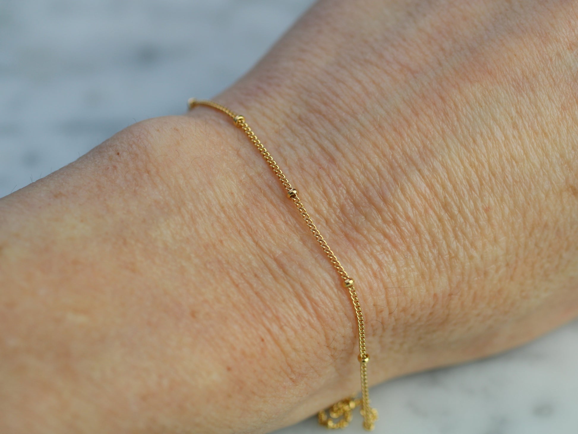 Gold bracelet on a wrist with a blurred background