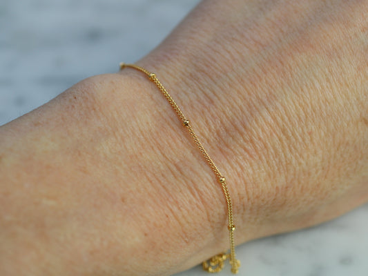 Gold bracelet on a wrist with a blurred background