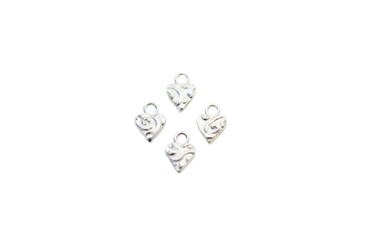 Four silver heart-shaped charms on a marble surface