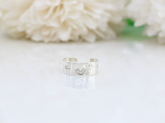 A silver heart-shaped ear cuff on a white surface