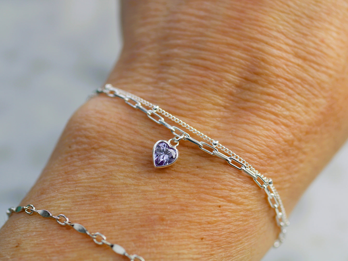 double layered bracelet with a heart charm on a wrist