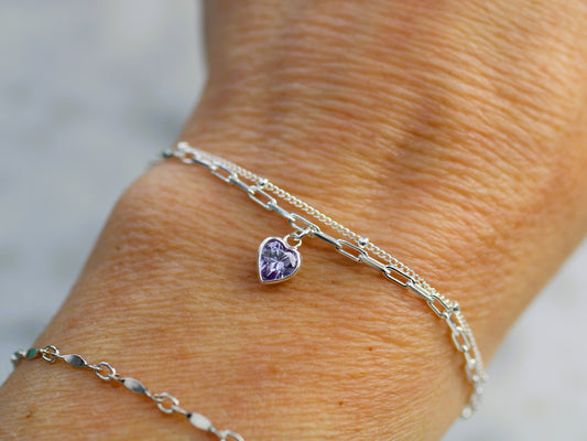 double layered bracelet with a heart charm on a wrist