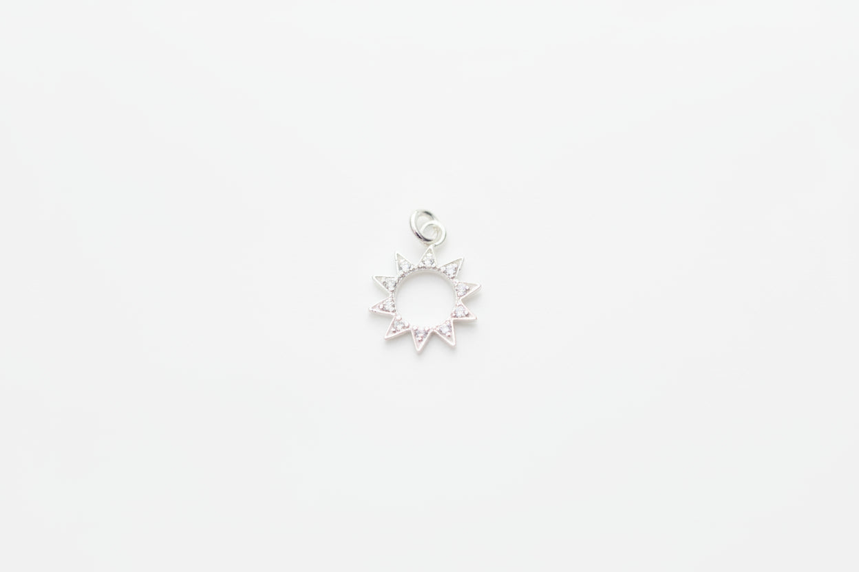 Silver sun-shaped pendant on a marble background
