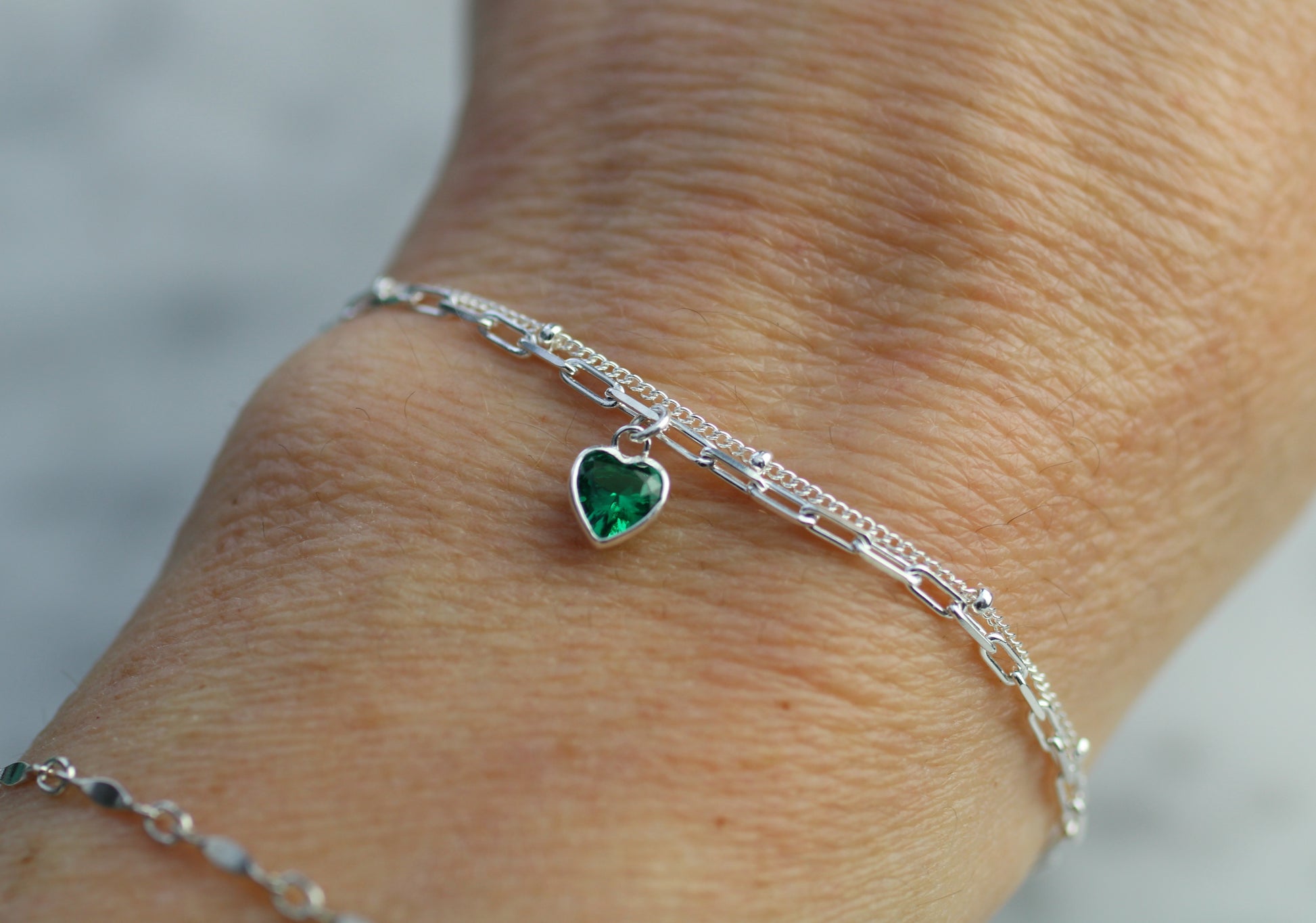 double layer chain with a heart charm worn on a wrist