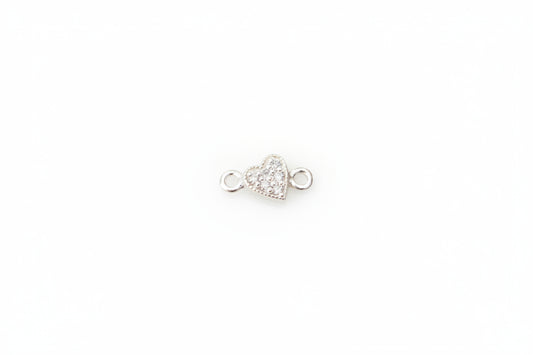 A small silver heart-shaped jewelry charm with moissanite displayed on a light gray marble surface.