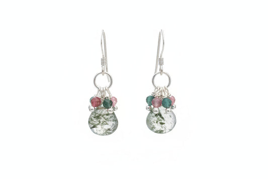 Teardrop-shaped earrings with green and pink beads on a white ceramic plate.