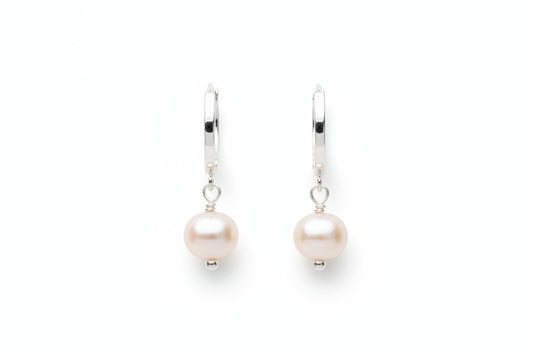 Silver hoop earrings with pearl drops on a marble surface