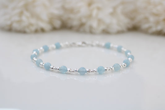 Baby blue beaded bracelet on a white surface with a soft white background