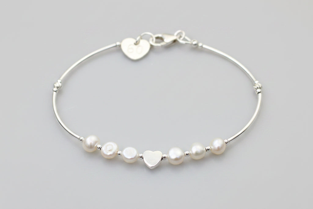 Silver bracelet with heart-shaped and round beads on a gray background
