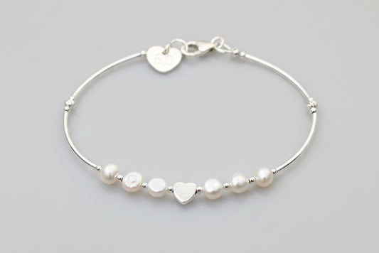 Silver bracelet with heart-shaped and round beads on a gray background