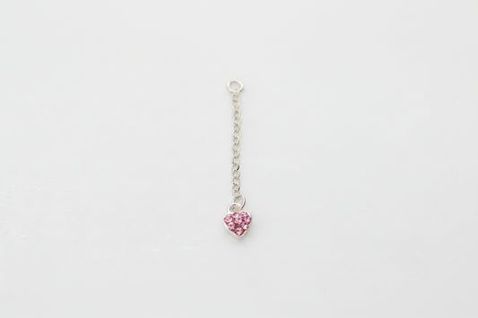 Pink heart-shaped pendant on a silver chain against a marble background