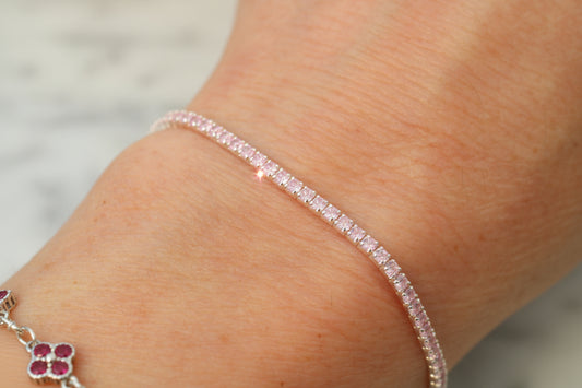 Close-up of a person's wrist wearing a pink bracelet on a neutral background