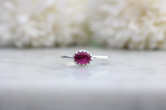 Silver ring with a purple gemstone on a white background