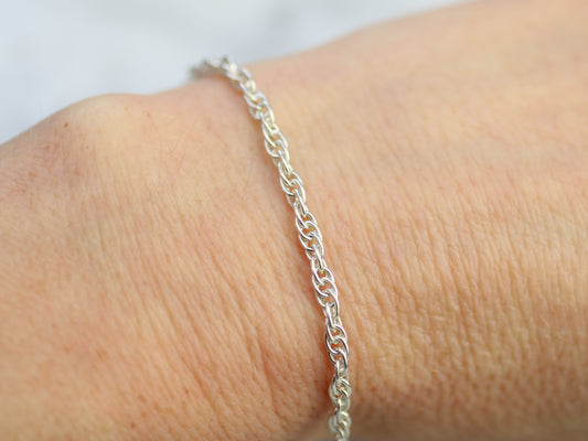 Silver bracelet on a person's wrist with a plain background