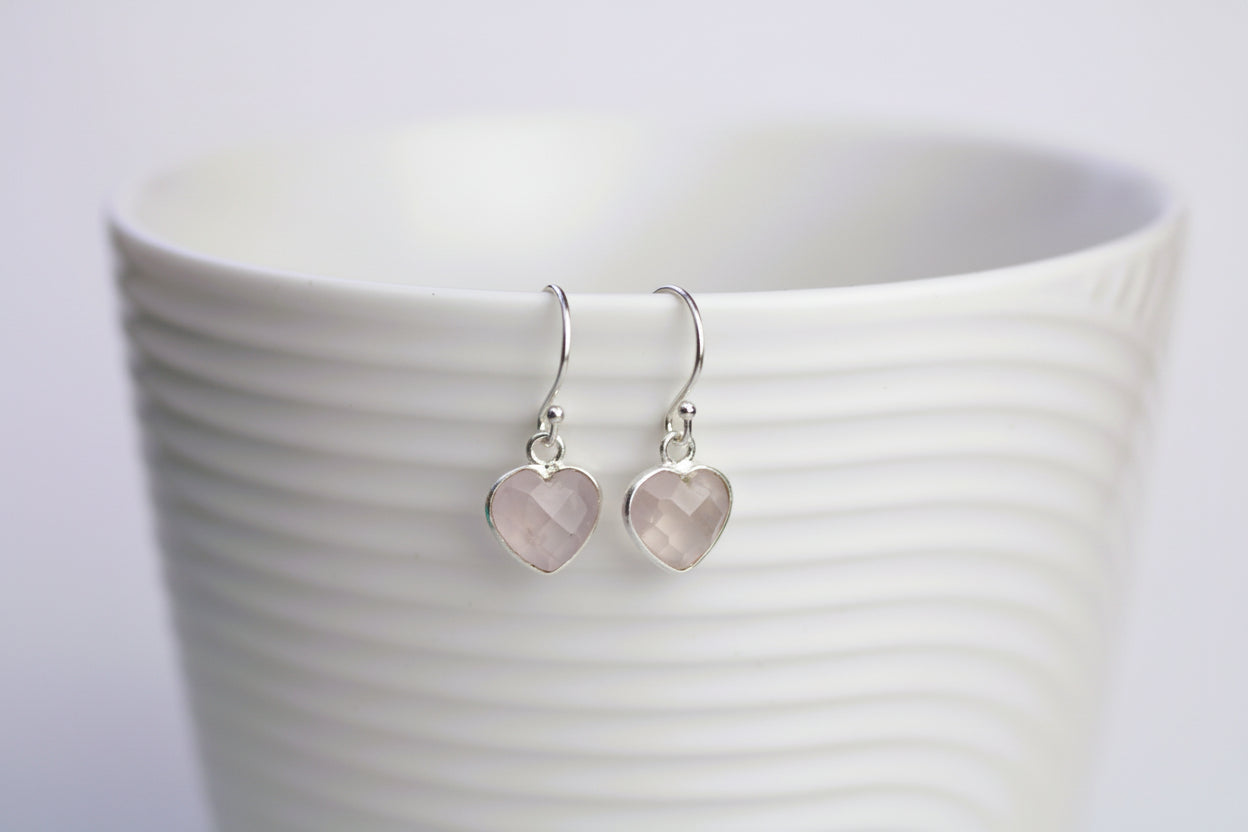 Heart-shaped earrings on a white cup with a blurred background