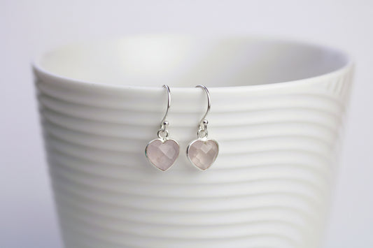 Heart-shaped earrings on a white cup with a blurred background