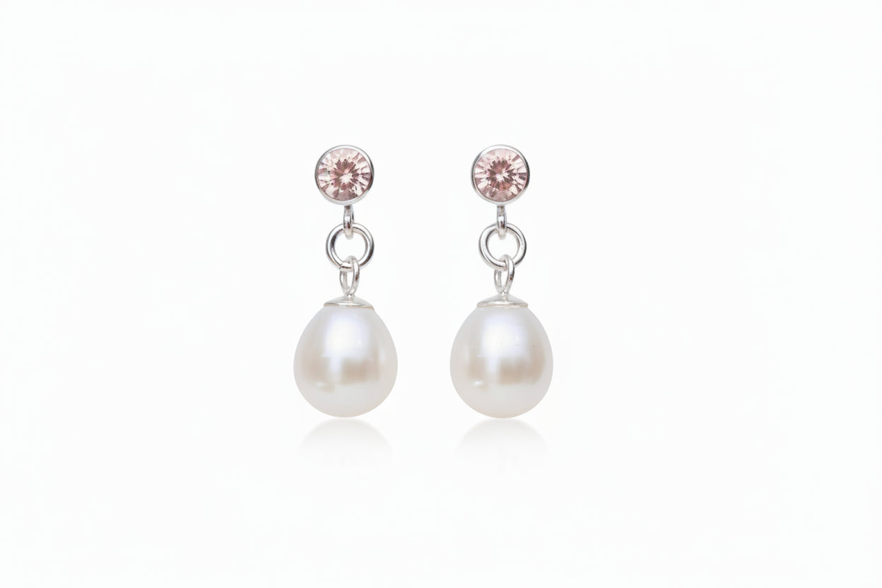 pink gemstone and pearl drop earrings with a white background